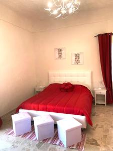 a bedroom with a large red bed with two white stools at Sicilia Benessere in Montedoro +7 photos