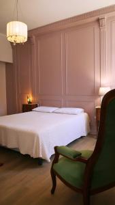 a bedroom with a bed and a green chair at La Belle Chartreuse in Manciet