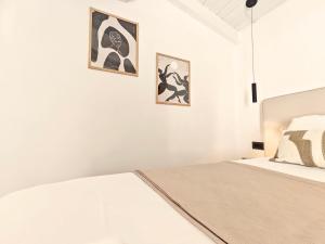a white bedroom with two pictures on the wall at Paxos Dream House in Vlachopoulátika