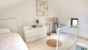 a white bedroom with a bed and a dresser at Stone House Perast in Kotor