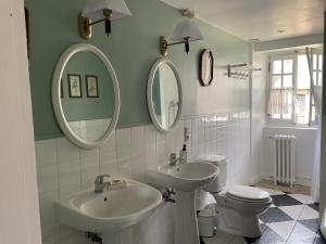 a bathroom with two sinks and a toilet and mirrors at Château de Saint-Pois in Saint-Pois