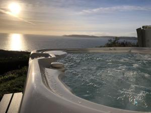 a hot tub with a view of the ocean at Crownhill Bay House in Plymouth