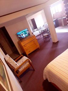 a bedroom with a bed and a dresser with a television at B&B Recoleta in Sucre
