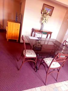 a glass table with two chairs and a vase with flowers at B&B Recoleta in Sucre