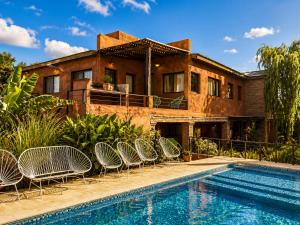 a house with a swimming pool and chairs next to it at Algarrobos del Mirador in Santa Rosa de Calamuchita