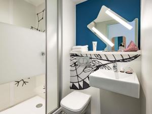 a bathroom with a sink and a toilet and a mirror at ibis Budget Beaune in Beaune