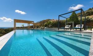 a swimming pool with two chairs and the ocean at Mistral Suite Heated Pool in Georgioupoli