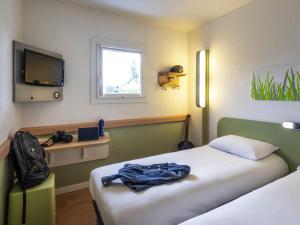a room with a bed and a tv and a bed sidx sidx sidx at Ibis budget Saint-Étienne stade in Saint-Étienne +88 photos