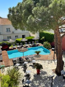 a pool with chairs and a tree next to a building at Hôtel Neptune in Balaruc-les-Bains