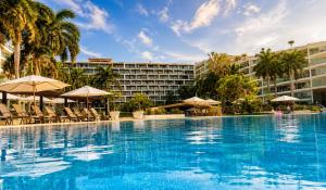 a large pool with chairs and umbrellas in front of a hotel at Aria Ocean in Nuevo Vallarta