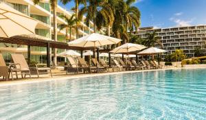 a swimming pool with chairs and umbrellas and a hotel at Aria Ocean in Nuevo Vallarta