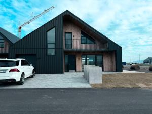 a house with a white car parked in front of it at ScenicOceanview 4Free parking space 18 mins Downtown in Álftanes