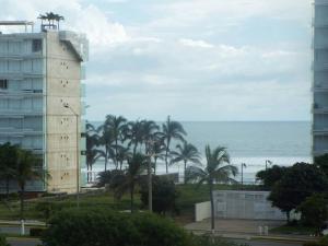 a tall building next to the ocean with palm trees at Puerta diamante acapulco in Acapulco +15 photos
