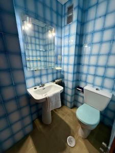 a blue tiled bathroom with a toilet and a sink at Casa Noël in Puertollano