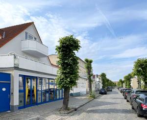 ein Baum vor einem Gebäude an einer Straße in der Unterkunft 2 Schlafzimmer, Offene Küche, Balkon und Terrasse - moderne 90qm in ruhiger, zentraler Lage - nur 500m bis zum Strand in Warnemünde
