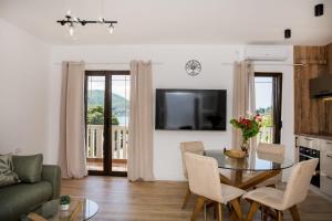 a living room with a table and chairs and a television at Studio Apartments Summer Time in Kamenari