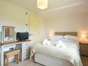 a white bedroom with a bed and a tv at Northrawe in Bamburgh