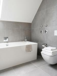 ein Badezimmer mit einer weißen Badewanne und einer Toilette in der Unterkunft 2 Schlafzimmer, Offene Küche, Balkon und Terrasse - moderne 90qm in ruhiger, zentraler Lage - nur 500m bis zum Strand in Warnemünde + 23 Fotos