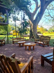 a group of benches in a park with a tree at Pousada Rainha da Mata in Penedo