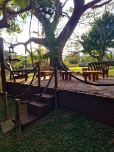 a park with benches and a tree and a hammock at Pousada Rainha da Mata in Penedo