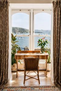 a room with a table and a view of the ocean at Ty'n Porth - By Rowes Retreats in Falmouth