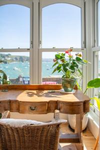 a table with a potted plant on it in front of a window at Ty'n Porth - By Rowes Retreats in Falmouth