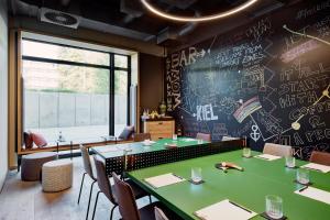 a dining room with a green table and a chalkboard wall at Me and All Hotel Kiel, by Hyatt in Kiel