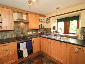 a kitchen with wooden cabinets and a sink at Tethera Cottage in Penrith
