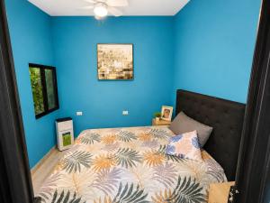 a bedroom with a bed with a blue wall at Jungle Serenity Haven in Cocles