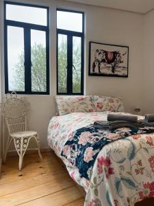 a bedroom with a bed and a chair and windows at FireFly Starry Woods Cabin in Keurboomstrand