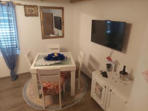 a room with a table and a tv on the wall at Villa Rafin dvor in Vrsi