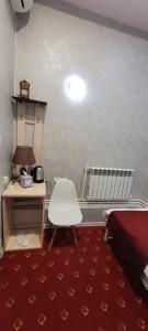a bedroom with a bed and a desk and a white chair at Hotel Erebuni Plaza in Yerevan
