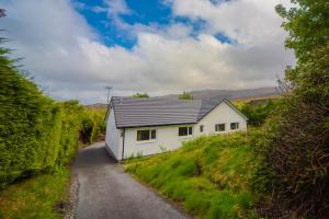 a white house with a grey roof on a road at Maisy's Hideaway in Kyleakin