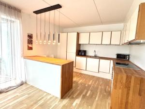 a kitchen with white cabinets and a wooden floor at Seafront Lux Apt, Central, Beach, Direct Airport Metro in Copenhagen +8 photos