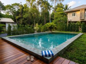 a swimming pool in a yard with a wooden deck at Villa Casa Blanca in Wok Tum