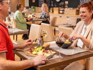 a man and woman sitting at a table with food and wine at ibis budget Lyon Est Chaponnay in Chaponnay