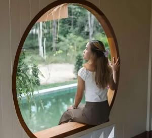 a woman sitting on a ledge looking out a window at Villa Casa Blanca in Wok Tum
