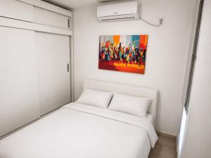 a bedroom with a white bed and a painting on the wall at Casa Mangrove in Maputo