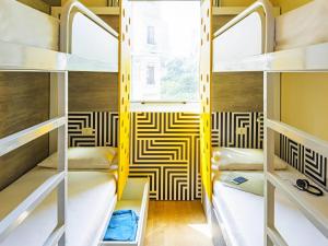 a room with bunk beds with a yellow and white patterned wall at ibis budget Rio de Janeiro Centro in Rio de Janeiro