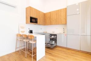 a kitchen with white cabinets and a counter with stools at ASTRO Emanuelle E by LovelyStay in Leça da Palmeira