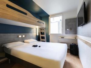 a bedroom with a large white bed and a television at ibis budget Meudon Paris Ouest in Meudon