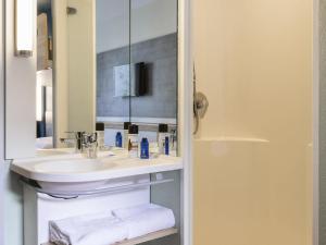a bathroom with a sink and a mirror at ibis budget Meudon Paris Ouest in Meudon +36 photos