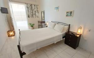 ein Schlafzimmer mit einem großen weißen Bett und einem Fenster in der Unterkunft Koukounari Rooms in Skala