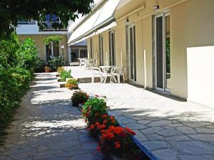 a patio with a table and flowers in front of a building at Elena Apartments in Keramoti