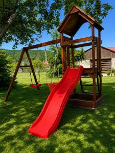 a playground with a red slide in a yard at Liliom Vendégház in Bakonybél