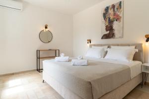 a bedroom with a large white bed with towels on it at Helen's 11 boutique in Achladies