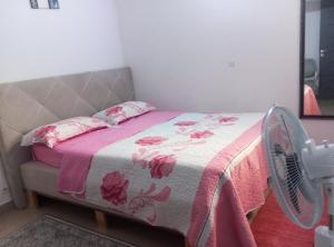 a bed with a pink blanket and a fan at Résidence cosy in Abidjan