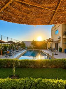 a swimming pool with a sunset in the background at Maison D'hôtes IMINIGRAN & Spa in Ouarzazate