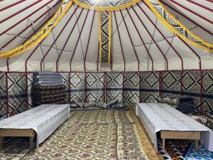 a tent with two beds and a rug in it at Murat Lyazzat Hotel in Kurmenty