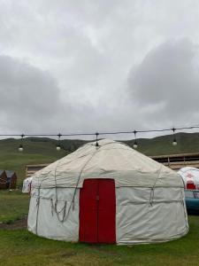 a white tent with a red door in a field at Murat Lyazzat Hotel in Kurmenty